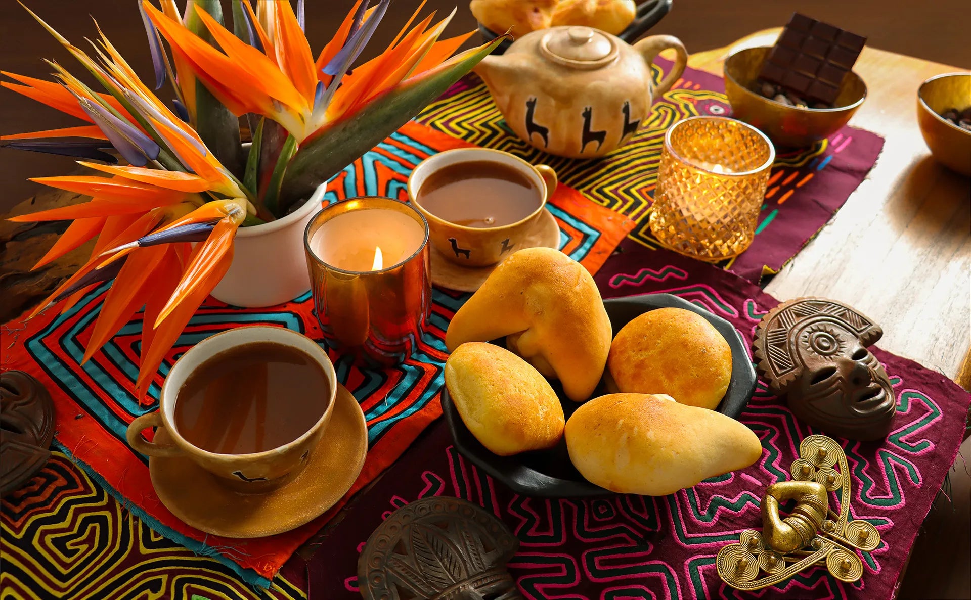 Ceremonial cacao drink with pan de bono pastries over colordul "mola" fabrics with tropical flowers